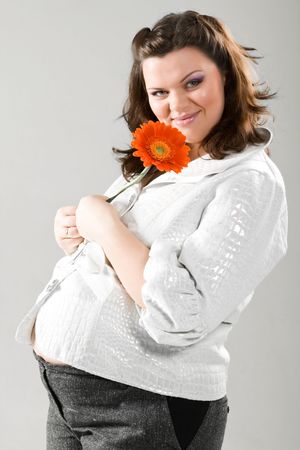 Beautiful pregnant young woman with flowerの写真素材