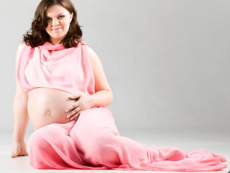 Portrait of beautiful pregnent woman in long pink dressの写真素材