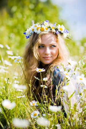 Beautiful young girl with diadem on camomile fieldの写真素材