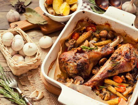 Dinner with turkey legs roasted with corn, garlic and rosemaryの写真素材