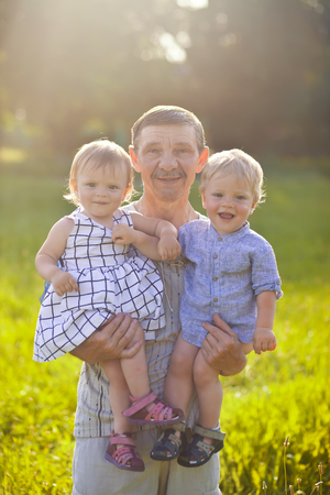 Grandfather with twins grandchildren in summer sunset