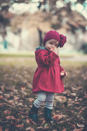 Little girl eat apple in autumn parkの写真素材