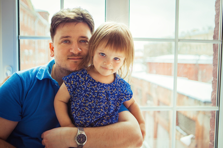 Father with little daughter at windowの写真素材