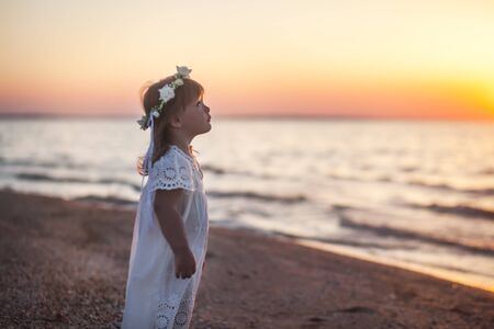 Little girl dreaming in sunset seaの写真素材
