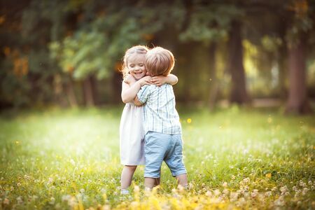 Funny little twins boy and girl in summer parkの写真素材