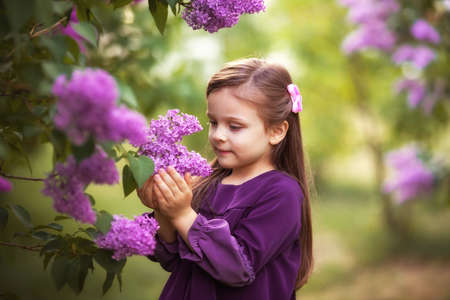 Beautiful kids twins boy and girl in spring garden with lilacの写真素材