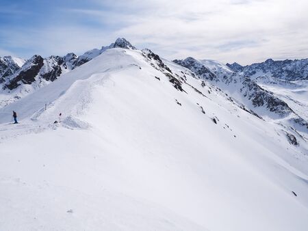 Skier on the slope and peaks of the mountains in the backgroundの写真素材
