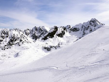 Skier on the slope and peaks of the mountains in the backgroundの写真素材