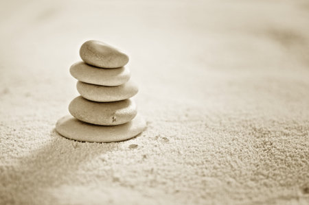 several zen stones on the sand background