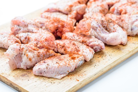 Raw chicken wings with spices on wooden boardの写真素材