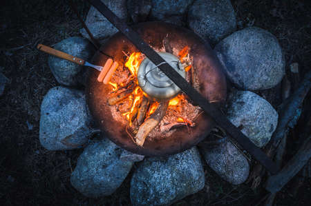 Metal kettle and grilled sausage on a campfireの写真素材