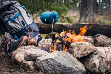 Camping in the woods. A backpack and a pair of trekking shoes on a stone.の写真素材