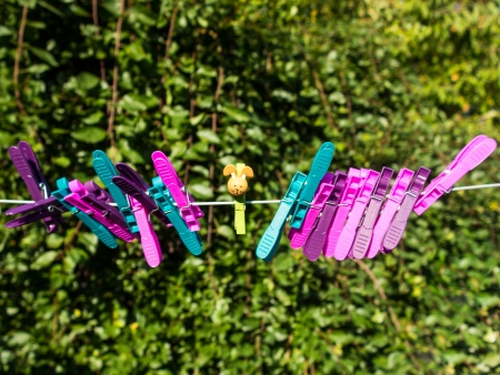 Colorful character plastic pegs on a line standing apart from the central lonely characterの写真素材