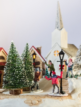A large and detailed closeup of a Christmas Village  Children playing snowballs in the illuminated street outside the Church  Shallow depth of fieldの写真素材