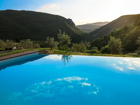 The horizon and reflections in an infinity swimming pool against a bright afternoon skyの写真素材