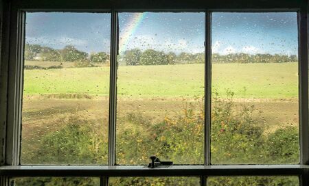 Looking out to a rainbow through a windowの写真素材