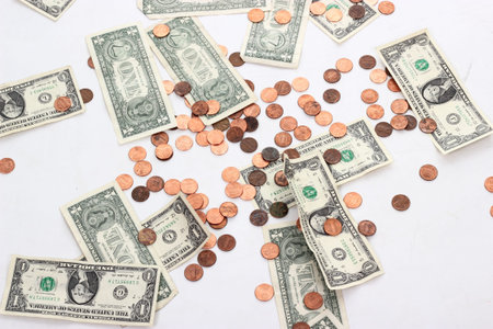 Dollar bills and pennies spread on a white background