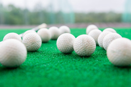 Golf balls on a synthetic grass mat at a practice range.