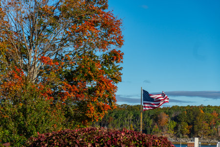 Autumn colors in America with United states flag waving in airの写真素材