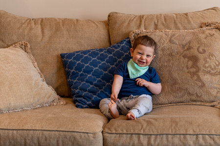 Cute little boy sitting on a sofa in the living room at home
