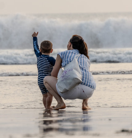 Mother and son playing on the beach at sunset time. Concept of friendly family.の写真素材