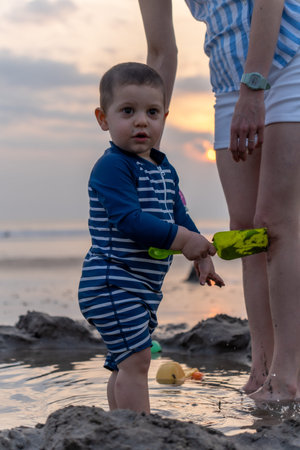 Little boy playing with toys on the beach at the sunset time.