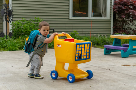 Little boy playing with a toy cart in the yard of his home