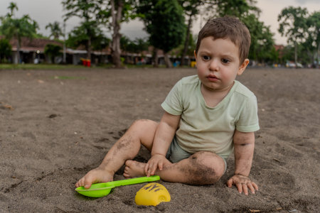 Cute little boy playing with sand on the beach in summer.の写真素材