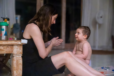 Mother playing with her baby at home, sitting on the floor.の写真素材