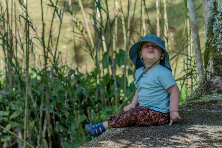 Little girl sitting on a stone in the middle of a bamboo forestの写真素材