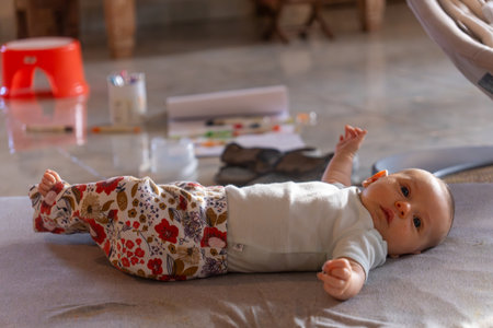 Cute little baby girl lying on the floor and playing with paintsの写真素材