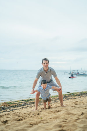 Father and son playing on the beach at the day time. Concept of friendly family.の写真素材