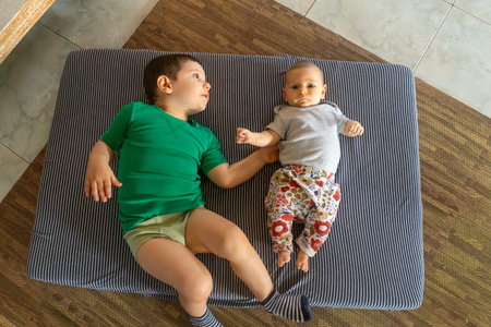 Top view of a boy playing with his newborn baby on a matの写真素材