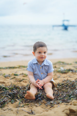 Portrait of a cute little boy sitting on the sea coast.の写真素材