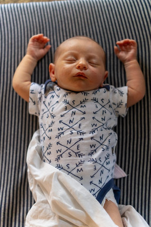 Newborn baby boy sleeping on a blue blanket in the nursery.