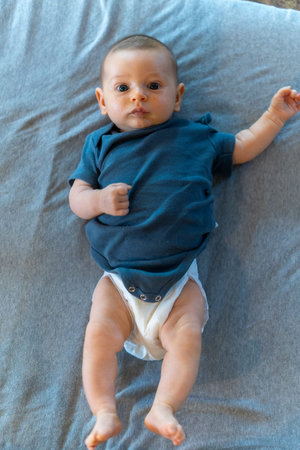 Cute baby boy lying on bed. Top view. Copy space.