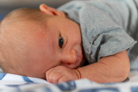 Newborn baby boy lying on his stomach and looking at the camera