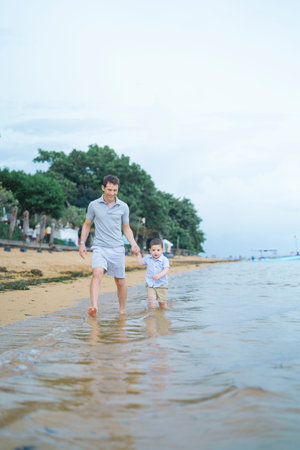 Father and son walking on the beach in summer. Happy family concept.