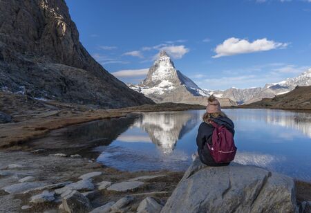 A young female hiker looks across a lake at the Matterhorn in Switzerland.の写真素材