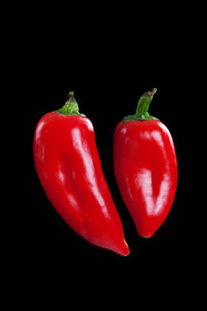 Two red hot peppers  in shape of heart shot on black の写真素材