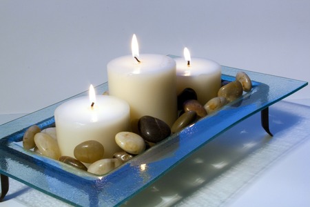Lit candles in a glass holder surrounded by rocks.の写真素材