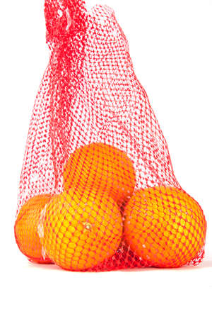 Oranges in a red net bag on a white background.の写真素材