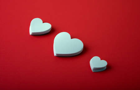 White foam hearts on a red background.の写真素材
