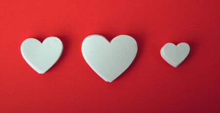 White foam hearts on a red background.の写真素材