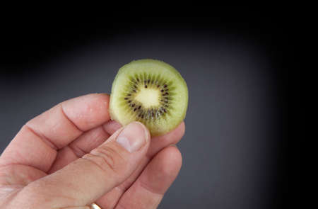 A hand holding a slice of kiwi.の写真素材
