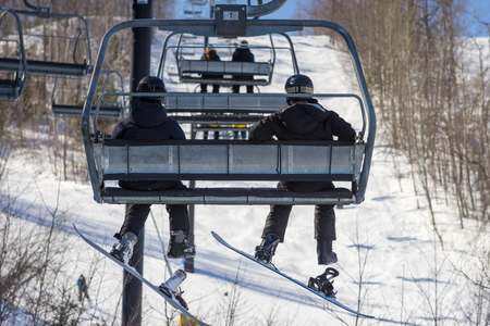 Two snowboarders ride the chairliftの写真素材