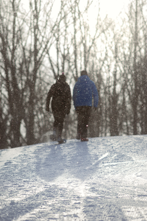 Couple walking up a snowy pathの写真素材