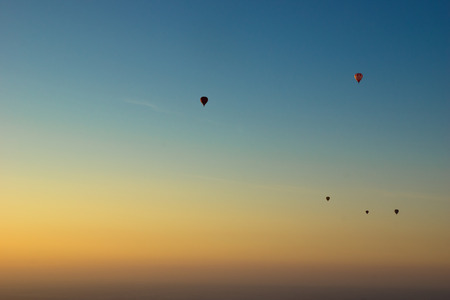 Hot air balloons float through the sky at sunriseの写真素材