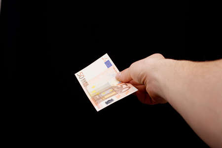 Hand giving money over blackの写真素材