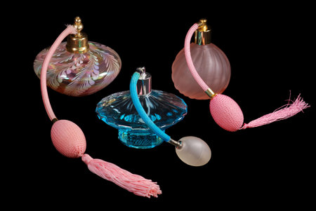 One blue and two pink perfume atomizers, on black iso background.